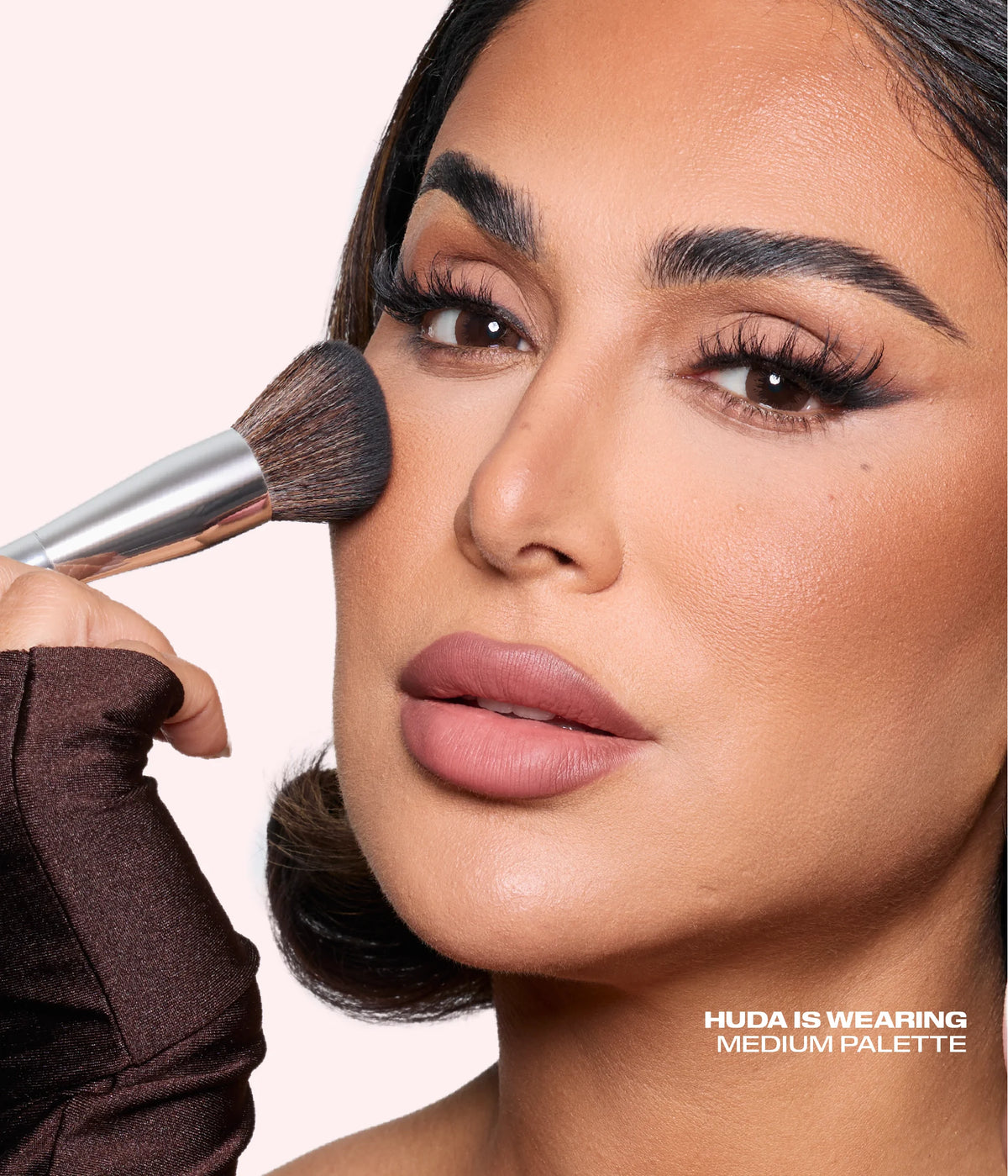 Huda Beauty founder Huda Kattan applying Bronze Filter Palette with the bronzing brush, with text 'Huda is wearing Medium palette'