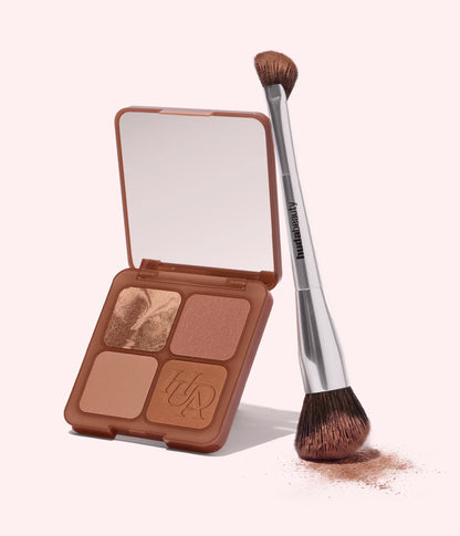 Huda Beauty Bronzer and Contour Brush leaning on an open Bronze Filter Palette with its mirror lid, powder dusted on the surface