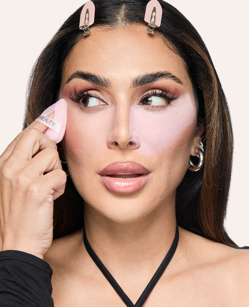 Huda Beauty applying setting powder under the eyes