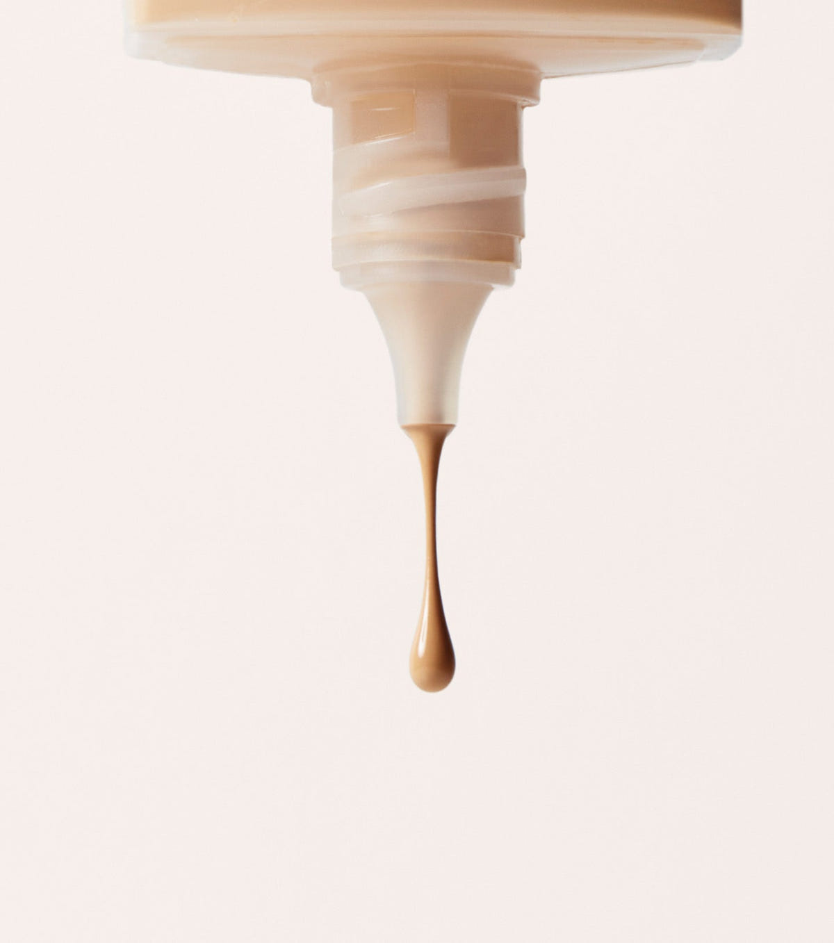 Huda Beauty Easy Blur Natural Airbrush Foundation, close-up of a tube nozzle with a drop of light beige foundation falling