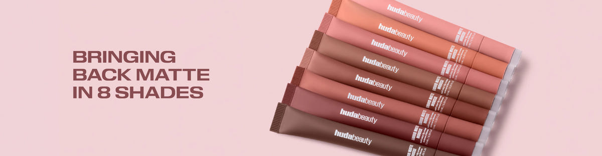 Huda Beauty Liquid Matte Mousse promotional banner with text 'Bringing back matte in 8 shades', showing eight mousse tubes fanned out on a pink background